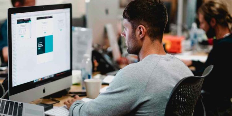 Auxiliar administrativo trabajando en oficina con ordenador en Adevinta, Torrejón de Ardoz, Madrid, oferta de empleo con sueldo de 1.750 euros.