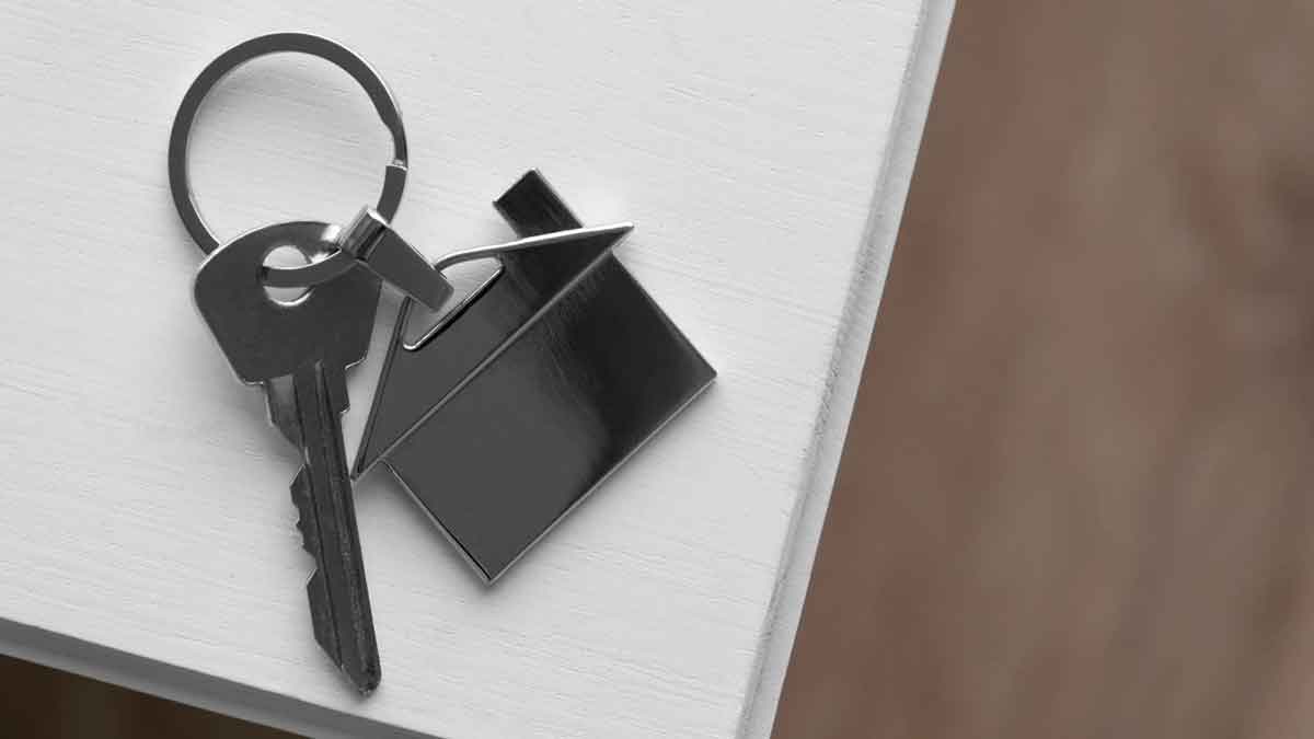 Llaves con llavero de casa sobre una mesa, representación del alquiler y ayudas a arrendatarios en la Comunidad de Madrid 2025.