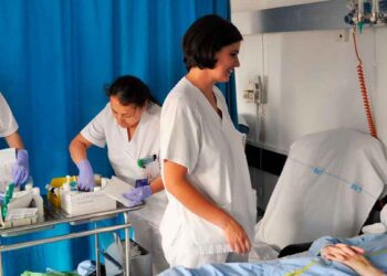 Enfermeras atendiendo a un paciente en un hospital de la Comunidad de Madrid, revisando material médico y suministros.