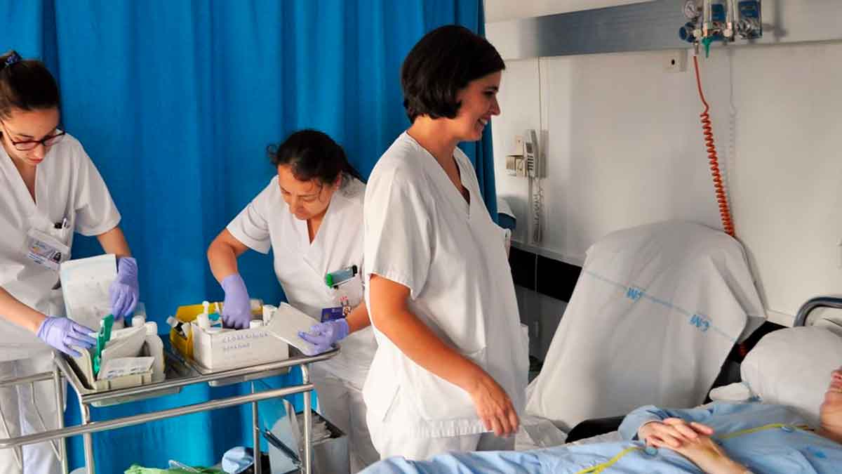 Enfermeras atendiendo a un paciente en un hospital de la Comunidad de Madrid, revisando material médico y suministros.