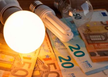 Evolución y subida del precio de la luz en 2025 en Madrid, bombilla iluminada sobre billetes de euro.