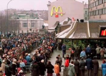 Clientes haciendo largas colas frente a McDonald’s para probar la nueva McExtreme Tutti Pepperoni en un día de invierno.