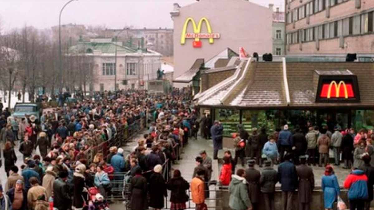 Clientes haciendo largas colas frente a McDonald’s para probar la nueva McExtreme Tutti Pepperoni en un día de invierno.