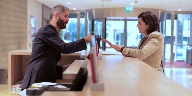 Recepcionista entregando documentos en empresa de Madrid, oferta de empleo para secretario con sueldo de 1.666 euros al mes.