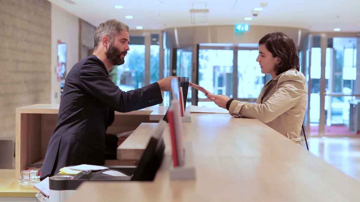 Recepcionista entregando documentos en empresa de Madrid, oferta de empleo para secretario con sueldo de 1.666 euros al mes.