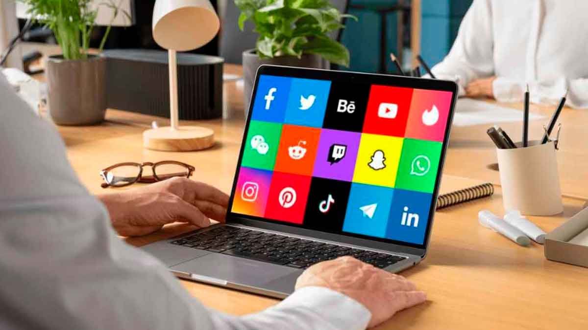 Pantalla de portátil mostrando iconos de redes sociales en oficina, relacionado con oferta de especialista en redes sociales en Madrid.