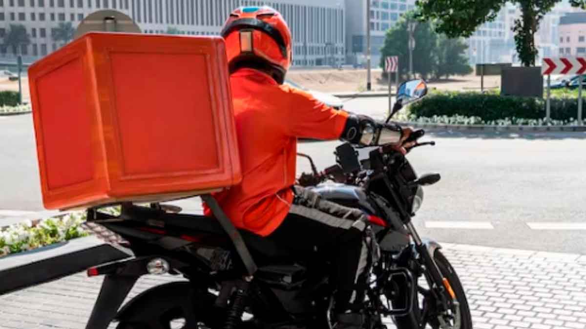 Repartidor en moto con caja de reparto en Coslada, Madrid, oferta de trabajo disponible sin estudios requeridos.