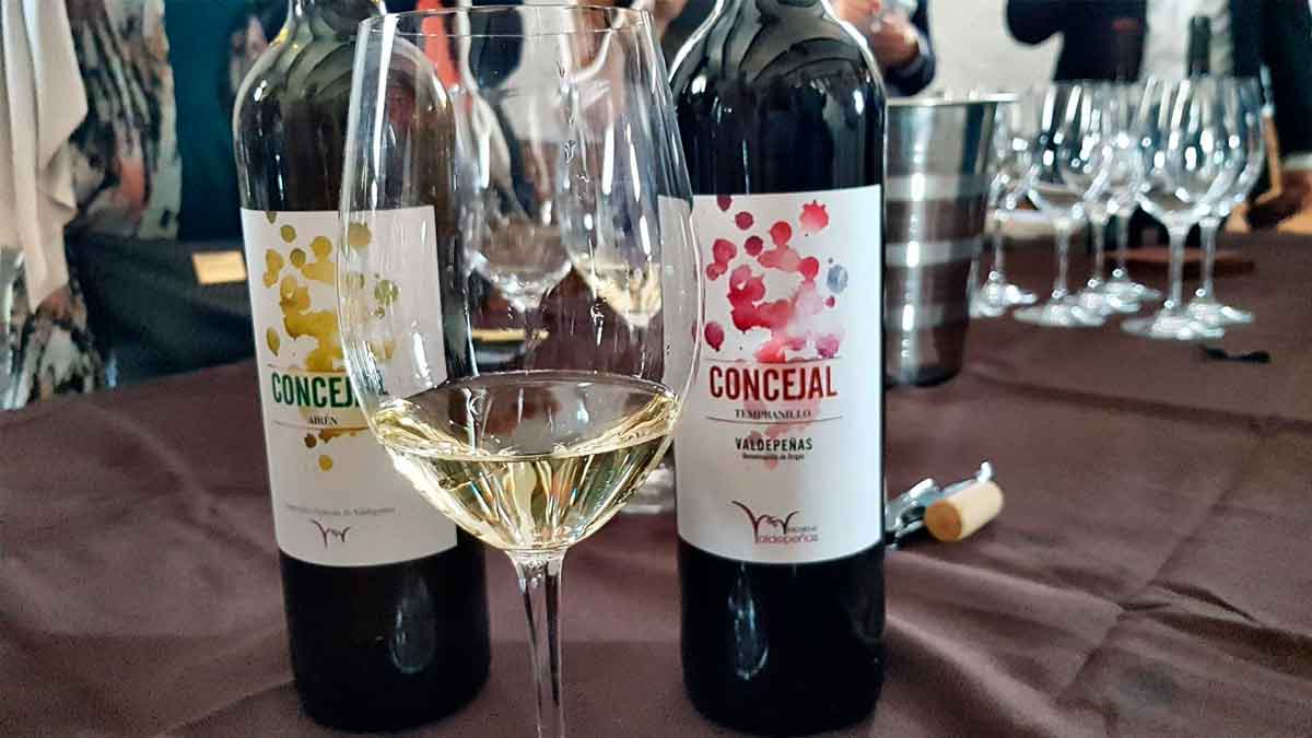 Botellas de vino Concejal D.O. Valdepeñas sobre una mesa con copa de vino blanco en primer plano.