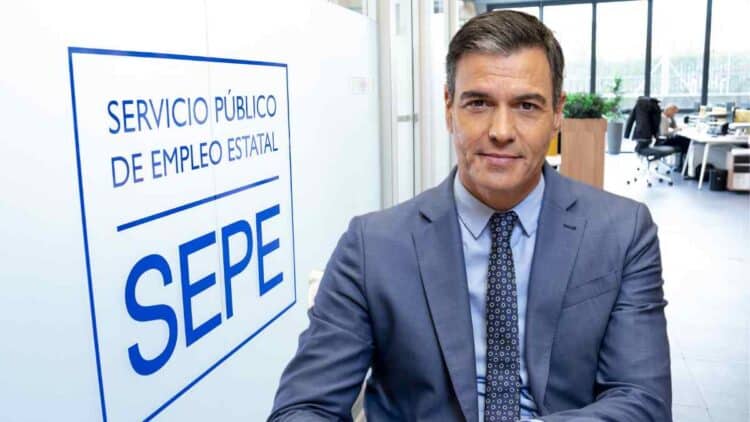 Pedro Sánchez frente a un cartel del Servicio Público de Empleo Estatal (SEPE), representando las novedades en prestaciones y subsidios para mayores de 52 años en 2025.