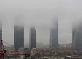 Vista de las Cuatro Torres de Madrid envueltas en niebla y cielo gris