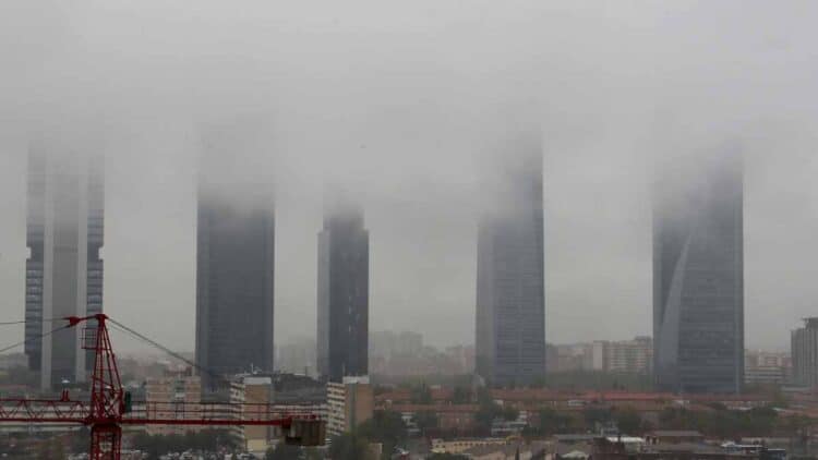 Vista de las Cuatro Torres de Madrid envueltas en niebla y cielo gris