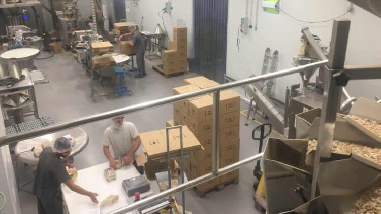 Trabajadores en una línea de envasado en Daganzo de Arriba, Madrid, manipulando productos y embalando cajas en una fábrica de pastelería.