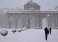 Puerta de Alcalá nevada en Madrid durante la borrasca Konrad, con transeúntes bajo intensas precipitaciones.