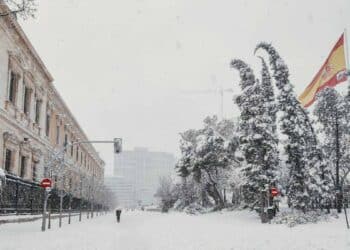 Calle de Madrid cubierta de nieve con la bandera de España al fondo, tras las intensas nevadas pronosticadas por la AEMET.