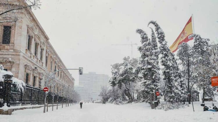 Calle de Madrid cubierta de nieve con la bandera de España al fondo, tras las intensas nevadas pronosticadas por la AEMET.