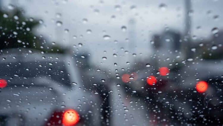 Parabrisas con gotas de lluvia y luces de vehículos difuminadas en Madrid durante un tren de borrascas