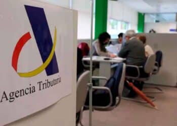 Logo de la Agencia Tributaria en una oficina mientras contribuyentes gestionan deudas inferiores a tres euros con Hacienda