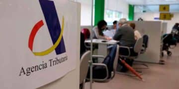 Logo de la Agencia Tributaria en una oficina mientras contribuyentes gestionan deudas inferiores a tres euros con Hacienda