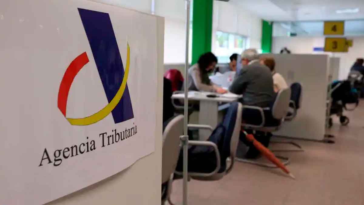 Logo de la Agencia Tributaria en una oficina mientras contribuyentes gestionan deudas inferiores a tres euros con Hacienda