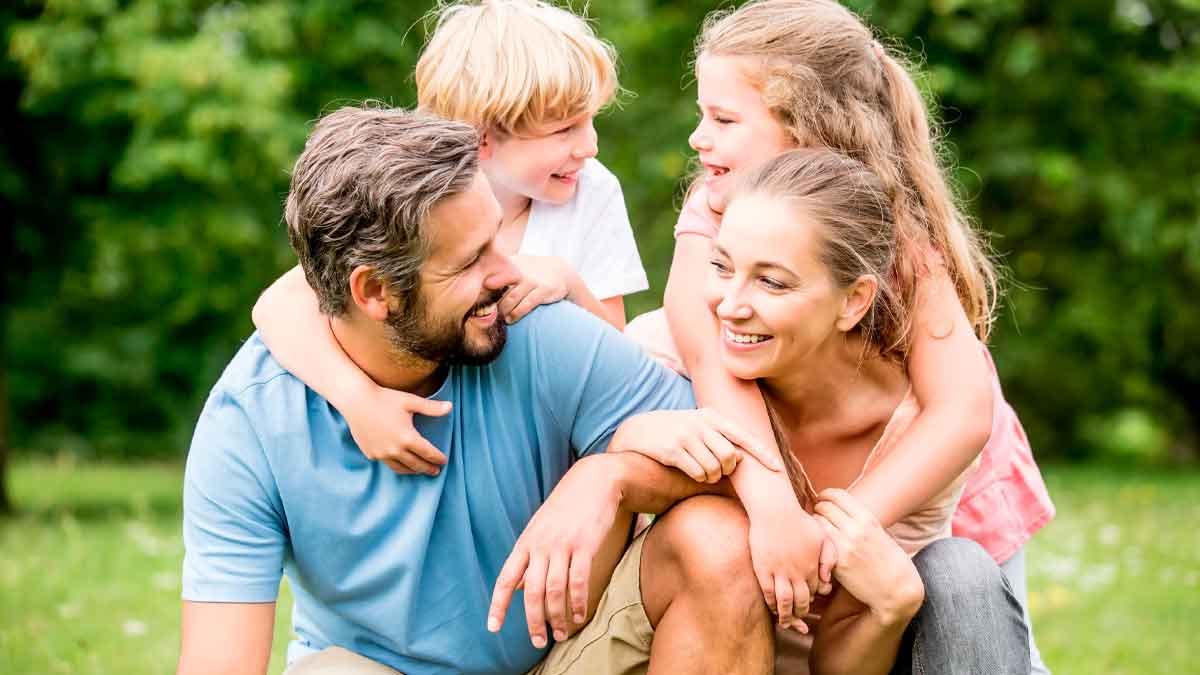 Familia con dos hijos disfrutando al aire libre, ejemplo de beneficiarios de la deducción de 300 y 900 euros de Hacienda