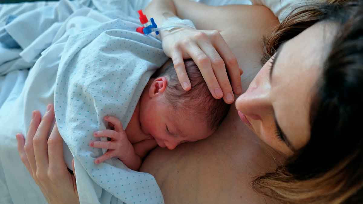 Madre joven sosteniendo a su bebé recién nacido en el hospital, ejemplo de la ayuda a la natalidad de la Comunidad de Madrid de 500 € al mes