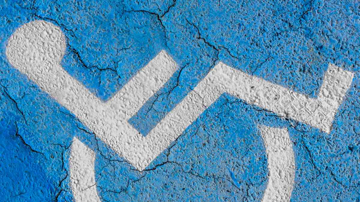 Símbolo de accesibilidad pintado en el suelo azul que representa la discapacidad y las ayudas para familias con hijos con necesidades especiales.