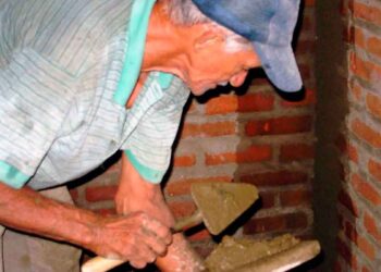 Hombre mayor trabajando como albañil tras la edad de jubilación, compatibilizando empleo y pensión