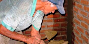 Hombre mayor trabajando como albañil tras la edad de jubilación, compatibilizando empleo y pensión