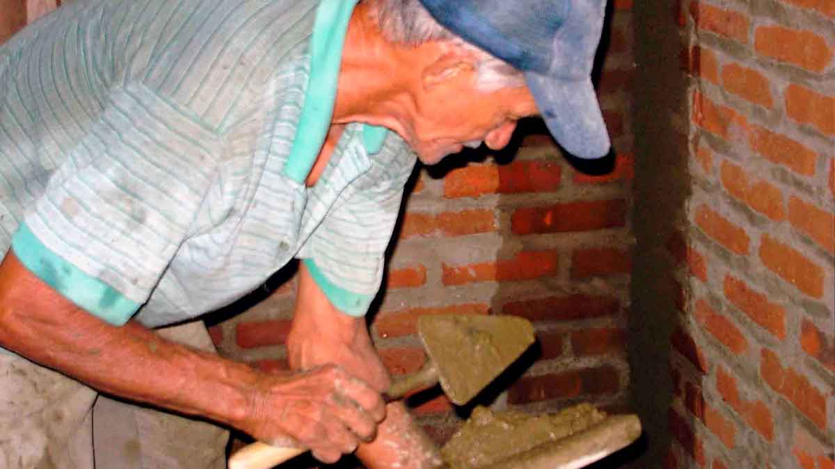 Hombre mayor trabajando como albañil tras la edad de jubilación, compatibilizando empleo y pensión