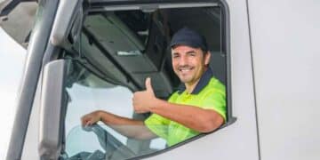 Conductor de camión saludando desde la cabina, ejemplo de profesional del transporte en España