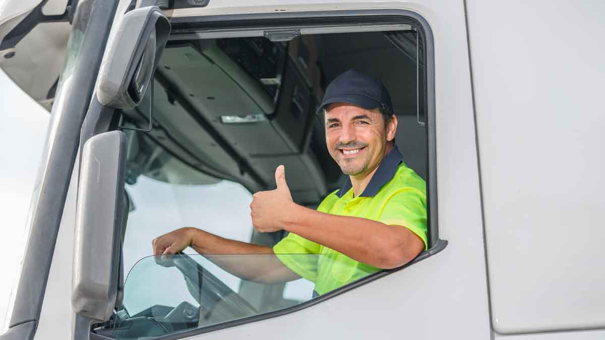Conductor de camión saludando desde la cabina, ejemplo de profesional del transporte en España