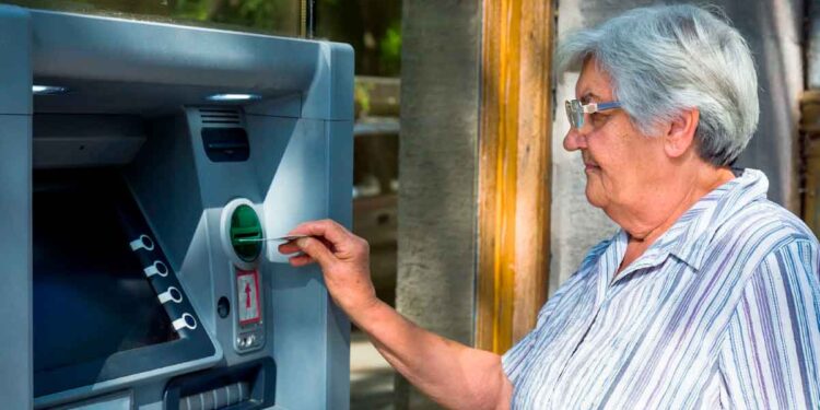 Mujer pensionista usando un cajero automático para retirar su pensión con el complemento de 140 euros anunciado por la Seguridad Social