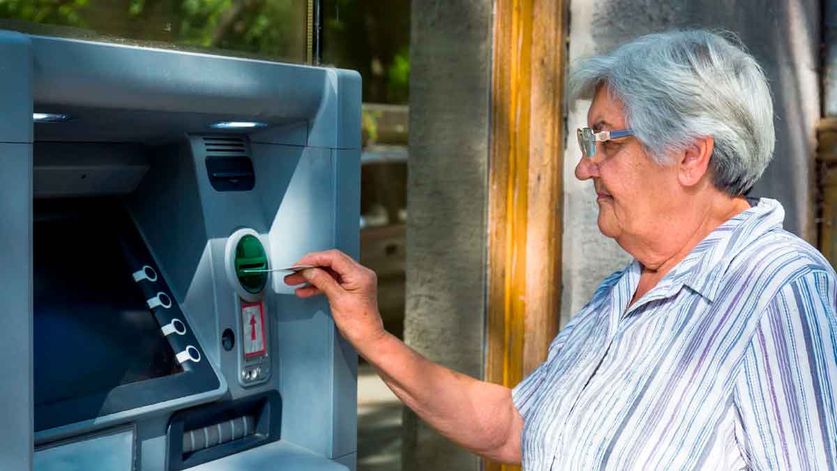 Mujer pensionista usando un cajero automático para retirar su pensión con el complemento de 140 euros anunciado por la Seguridad Social