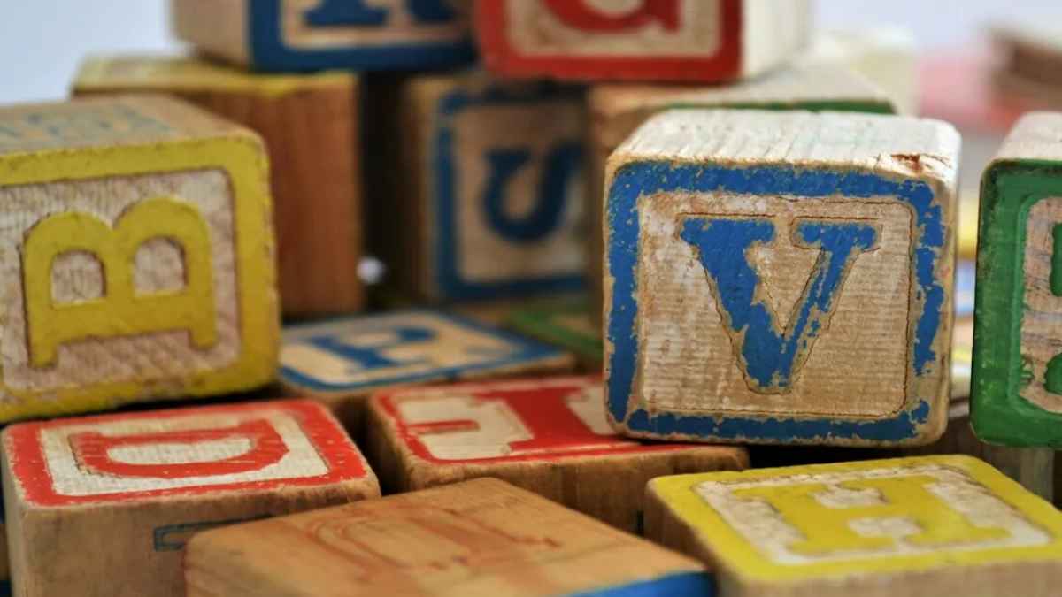 Bloques de madera con letras de colores, destacando la letra V, para ilustrar la importancia de diferenciar la B de la V