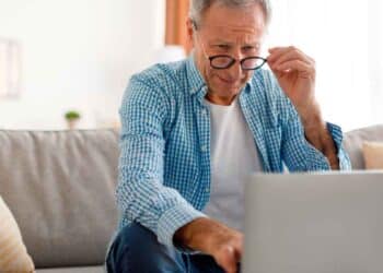 Hombre mayor consulta información sobre planes y fondos de pensiones en su ordenador portátil desde casa