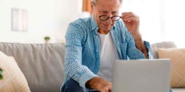 Hombre mayor consulta información sobre planes y fondos de pensiones en su ordenador portátil desde casa
