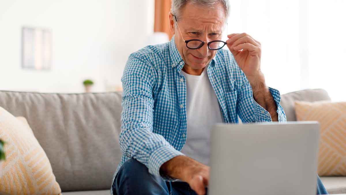 Hombre mayor consulta información sobre planes y fondos de pensiones en su ordenador portátil desde casa