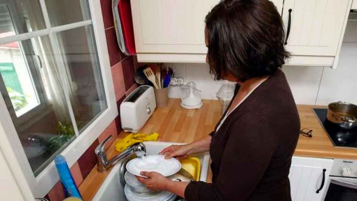Ama de casa lavando platos en la cocina, ilustrando la nueva pensión de 500 euros para quienes cumplen 2 requisitos