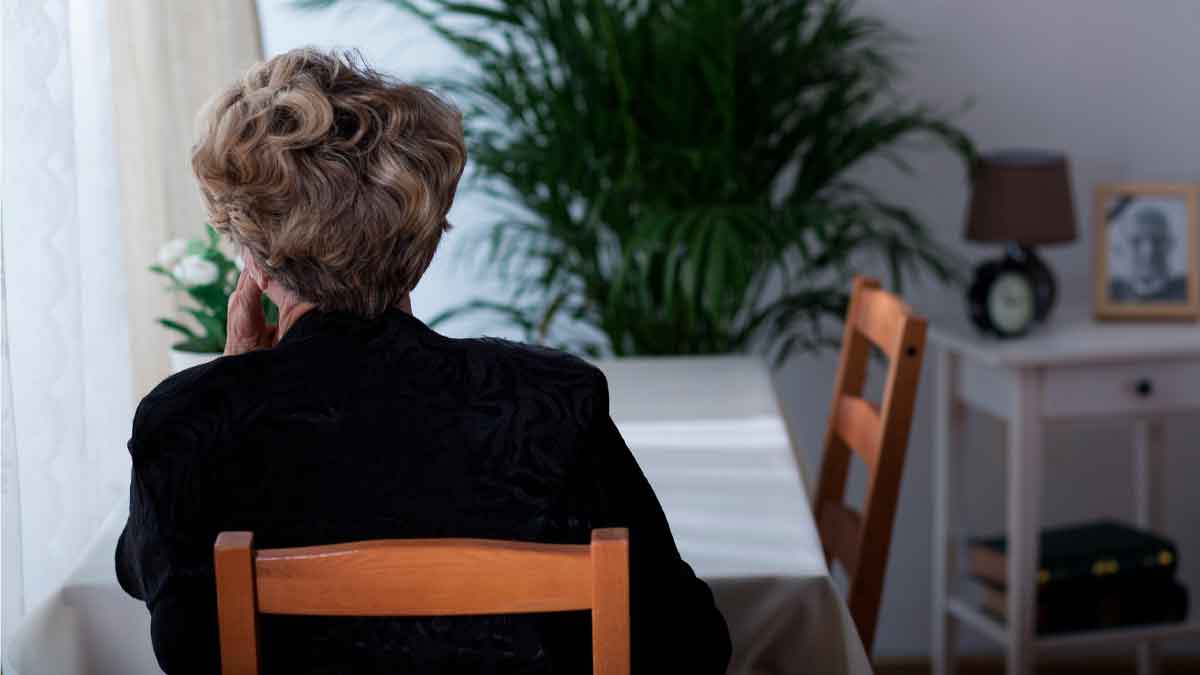 Mujer mayor de espaldas, sola en casa tras perder a su cónyuge; ejemplo real de beneficiaria de la pensión de viudedad de la Seguridad Social