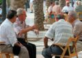 Grupo de jubilados sentados al aire libre conversando en una plaza pública en España