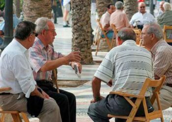 Grupo de jubilados sentados al aire libre conversando en una plaza pública en España