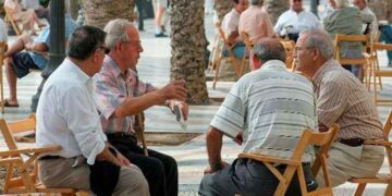 Grupo de jubilados sentados al aire libre conversando en una plaza pública en España
