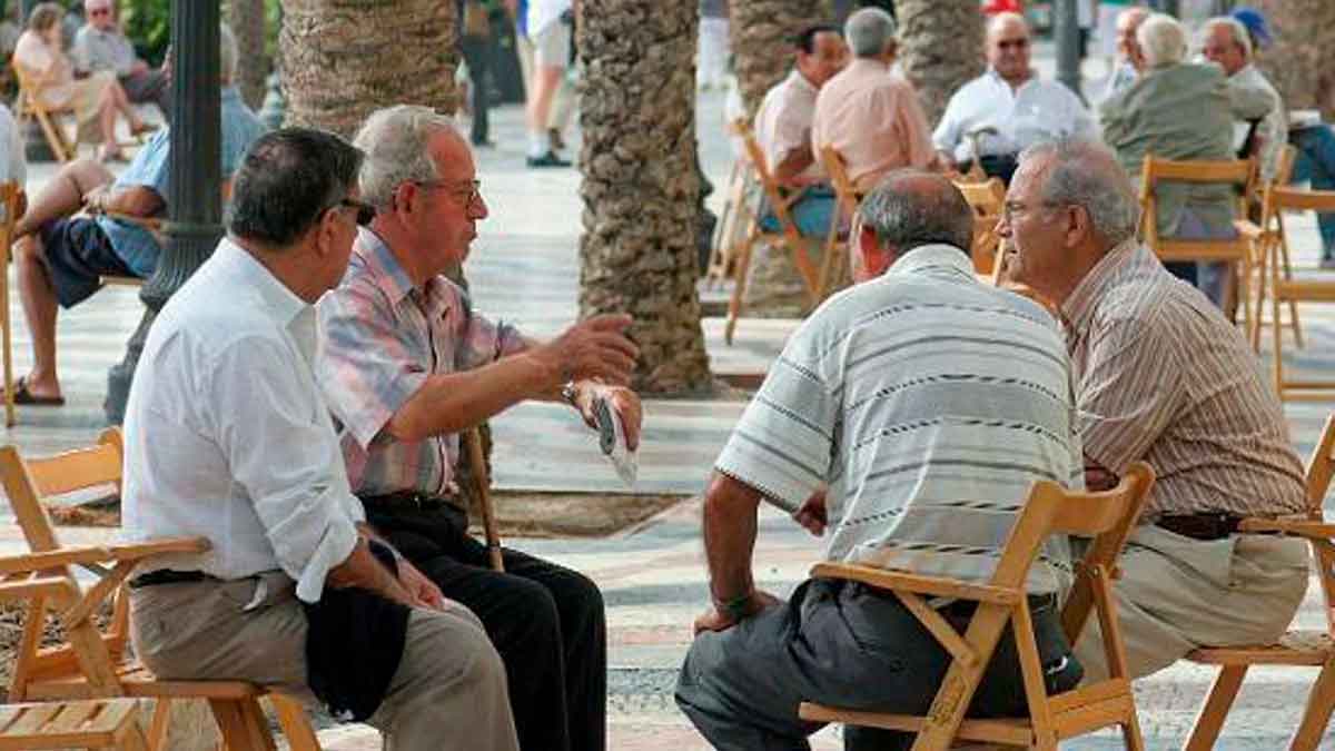 Grupo de jubilados sentados al aire libre conversando en una plaza pública en España