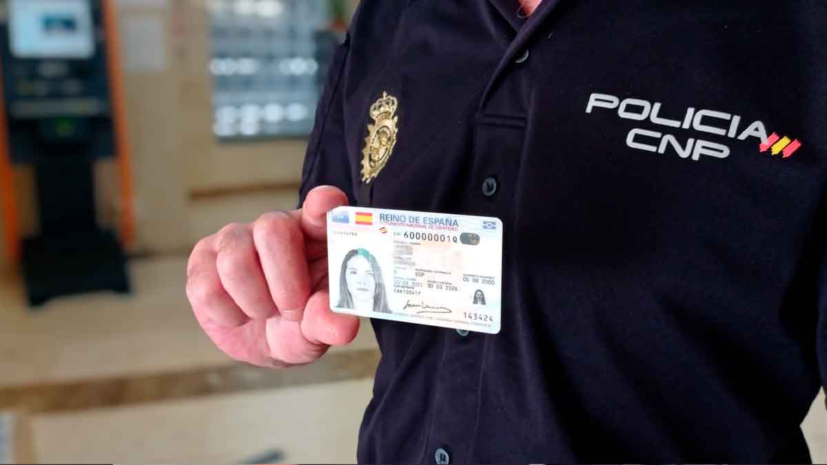 Agente de la Policía Nacional sosteniendo un DNI y alertando a la población española sobre su uso y renovación