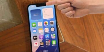 Persona señalando la parte superior de un iPhone, donde se ve el indicador verde o naranja que alerta sobre el uso de cámara o micrófono