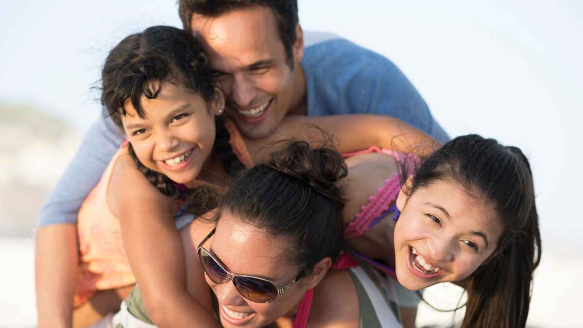 Padre, madre y dos hijas sonriendo mientras disfrutan de un momento familiar