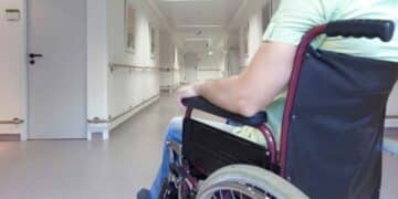 Hombre en silla de ruedas en un pasillo de hospital, representando la retirada y restitución de una pensión por incapacidad absoluta