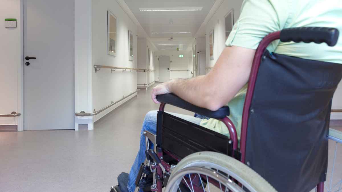 Hombre en silla de ruedas en un pasillo de hospital, representando la retirada y restitución de una pensión por incapacidad absoluta