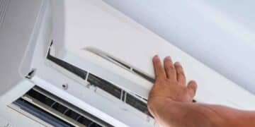 Hombre comprobando el funcionamiento de un aire acondicionado en busca de alternativas más eficientes para ahorrar hasta un 70% en la factura