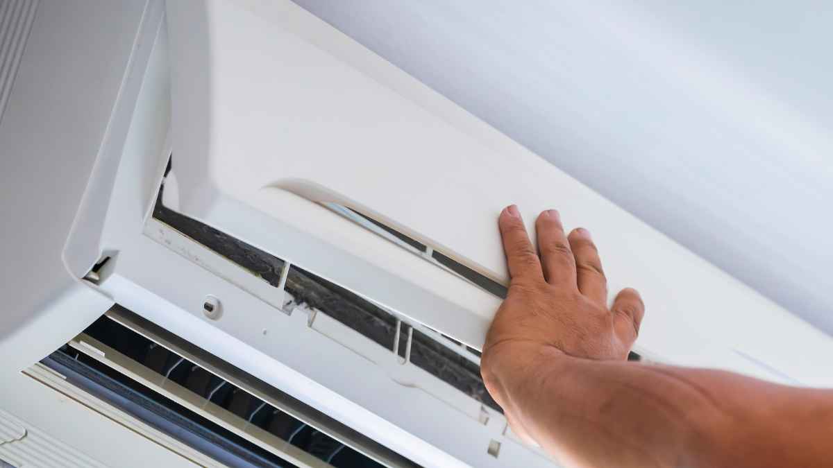 Hombre comprobando el funcionamiento de un aire acondicionado en busca de alternativas más eficientes para ahorrar hasta un 70% en la factura